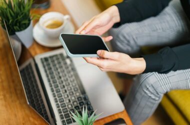 person using smartphone and laptop in office setting