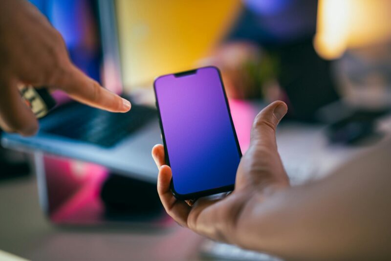 hands pointing at smartphone with gradient screen