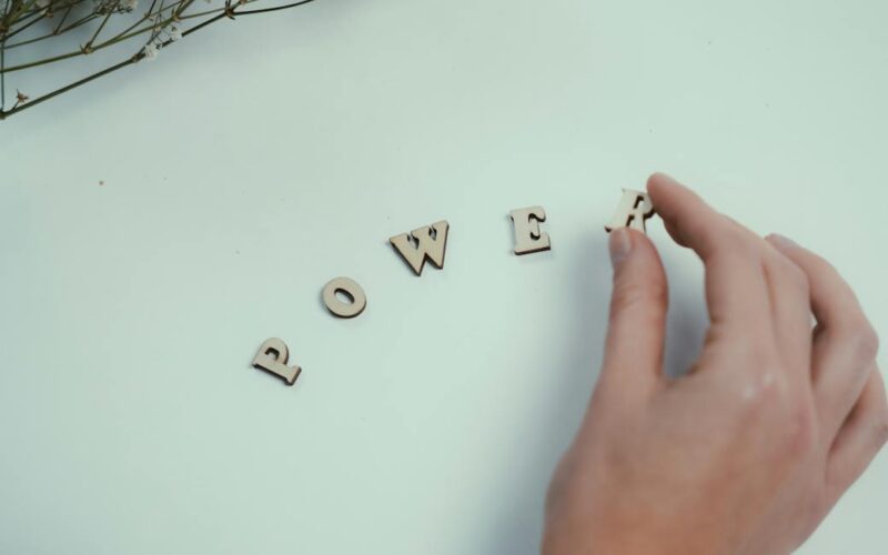 hand arranging wooden letters spelling power